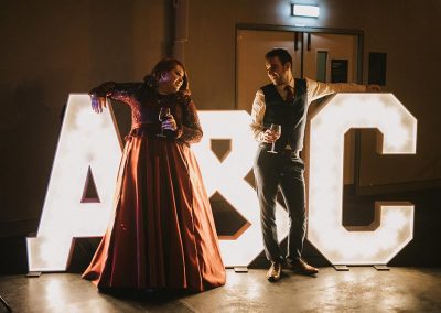 Bride and groom standing by their initials in large light up letters