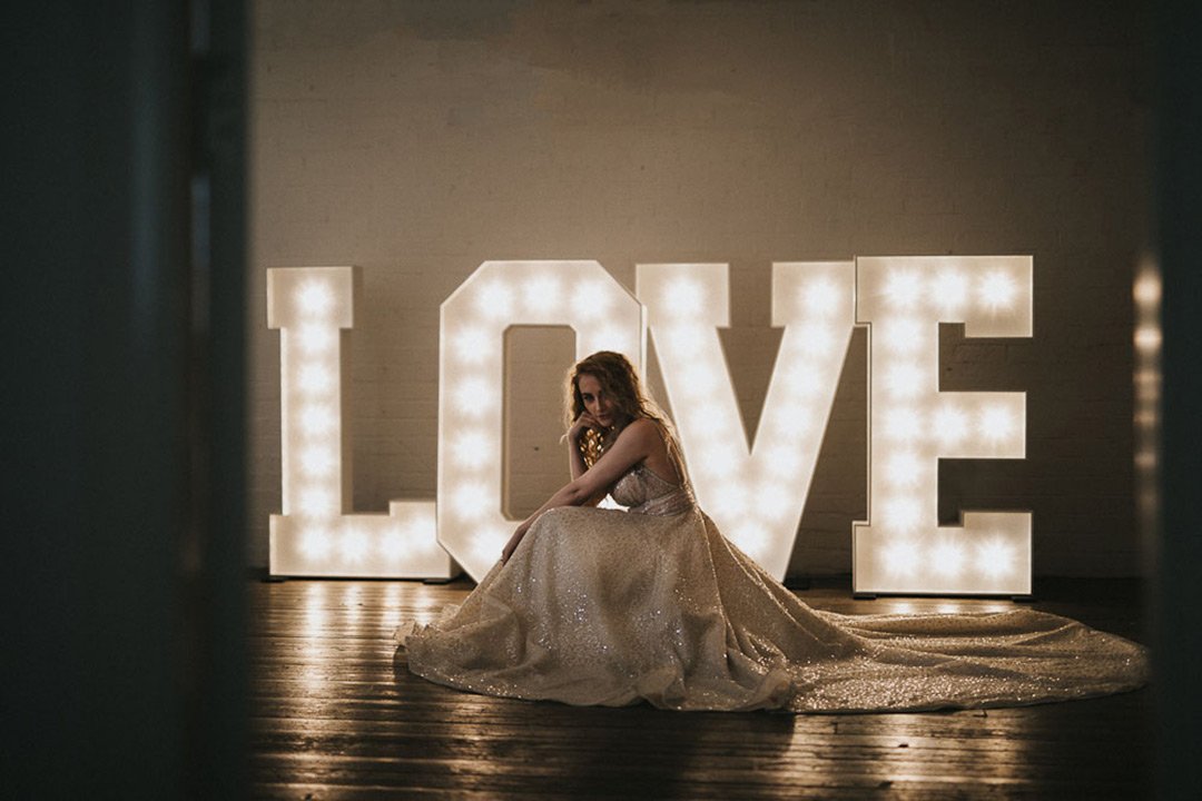 LOVE in large lighted letters with bride in front